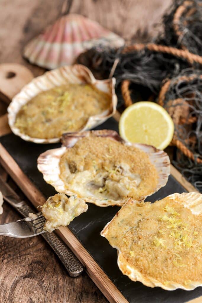 Coquilles saint-jacques farcies sur table en bois rustique avec un vieux filet de pêche | Aux Fourneaux recette de coquilles Saint Jacques à la Bretonne repas de Noel