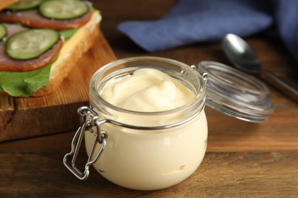 Jar of delicious mayonnaise near fresh sandwich on wooden table | Aux Fourneaux Mayonnaise sans œuf cru recette inratable