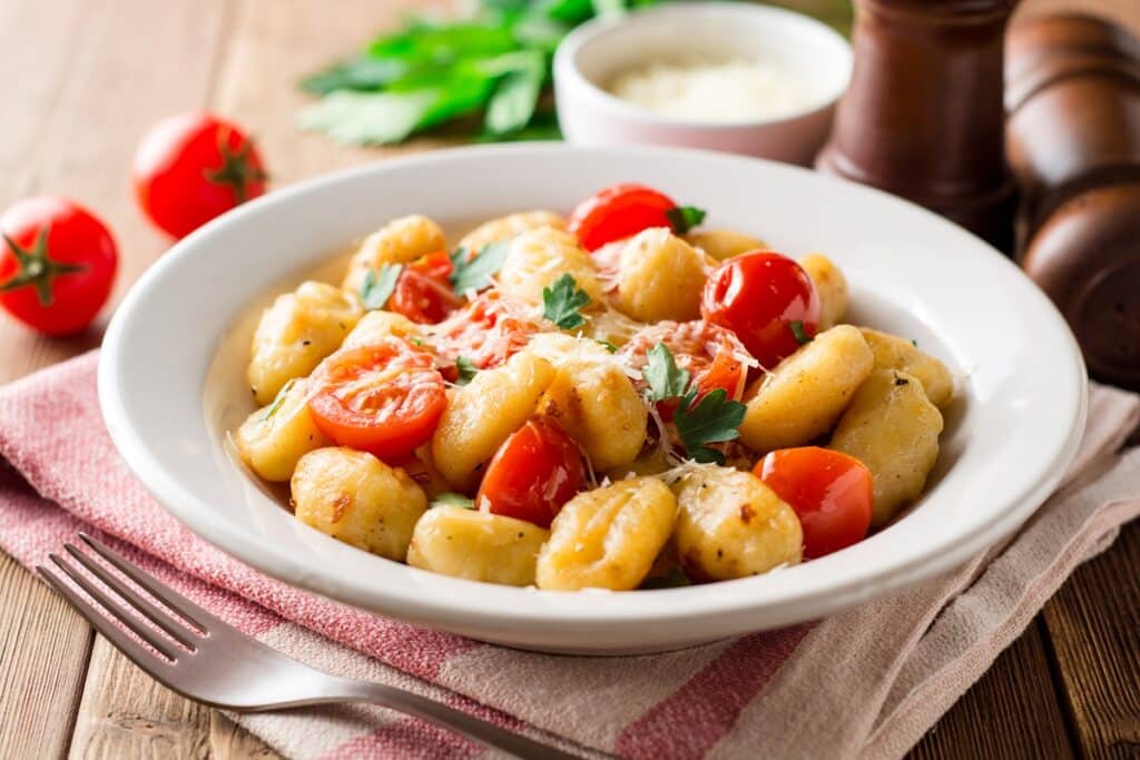 Homemade italian gnocchi with tomato garlic parsley and parmesan cheese on wooden table | Aux Fourneaux Gnocchi poêlés au Air Fryer faciles et rapides