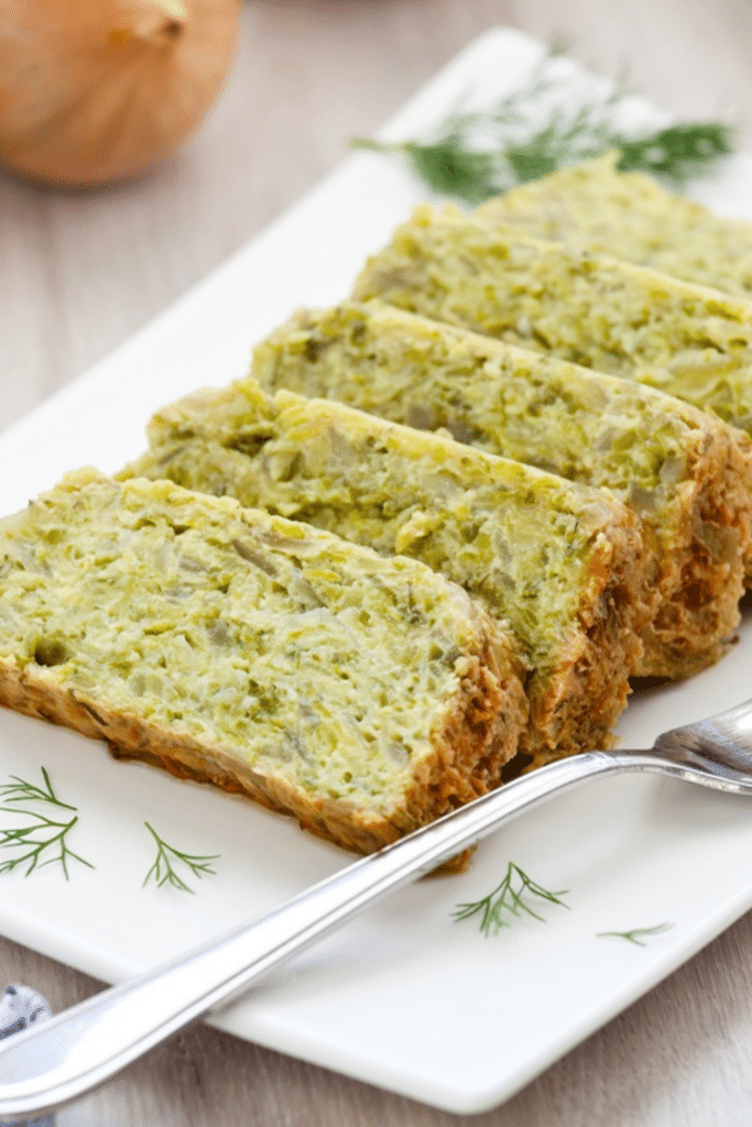 Flan de courgettes diététique facile rapide et léger | Aux Fourneaux Slices of herb-infused loaf on a white plate with dill garnish and a nearby fork.