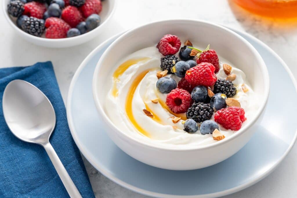 Greek yogurt bowl with raspberries blueberries blackberries almonds and honey for breakfast Healthy tasty snack Selective focus | Aux Fourneaux Quels sont les bienfaits du yaourt grec pour la santé